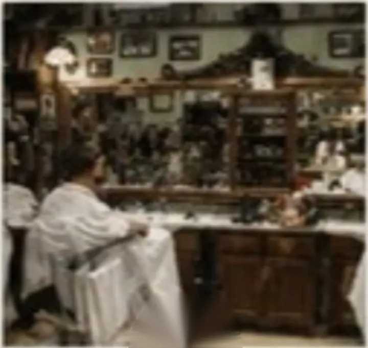 Un cliente in poltrona nella sala della bottega, sotto le specchiere
